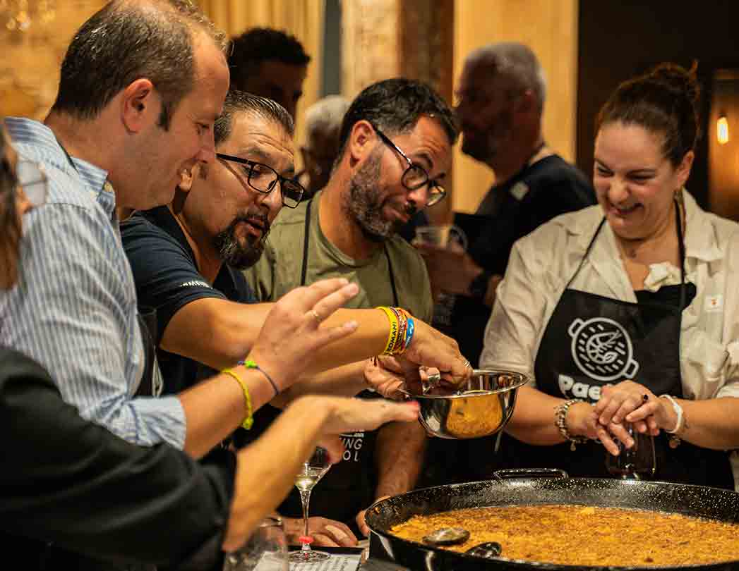 Photo of a paella workshop for companies in Barcelona where the team cooks together and collaborates in interconnected steps. Culinary team building activity with defined responsibilities, participation from everyone and a focus on cohesion, communication and collective success.
