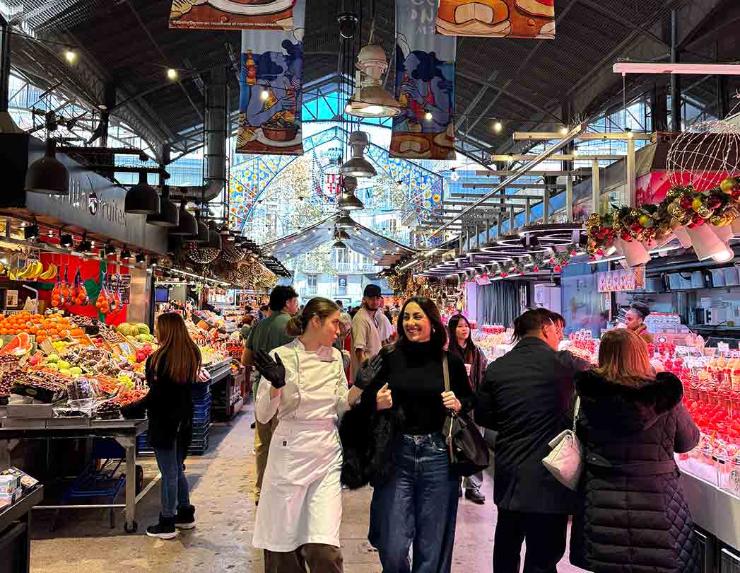 Photo of La Boqueria Market in Barcelona during the start of the culinary team building: the group carries out a shopping challenge with a budget to select fresh ingredients before the paella workshop. Authentic experience for companies that promotes collaboration, negotiation and decision-making.